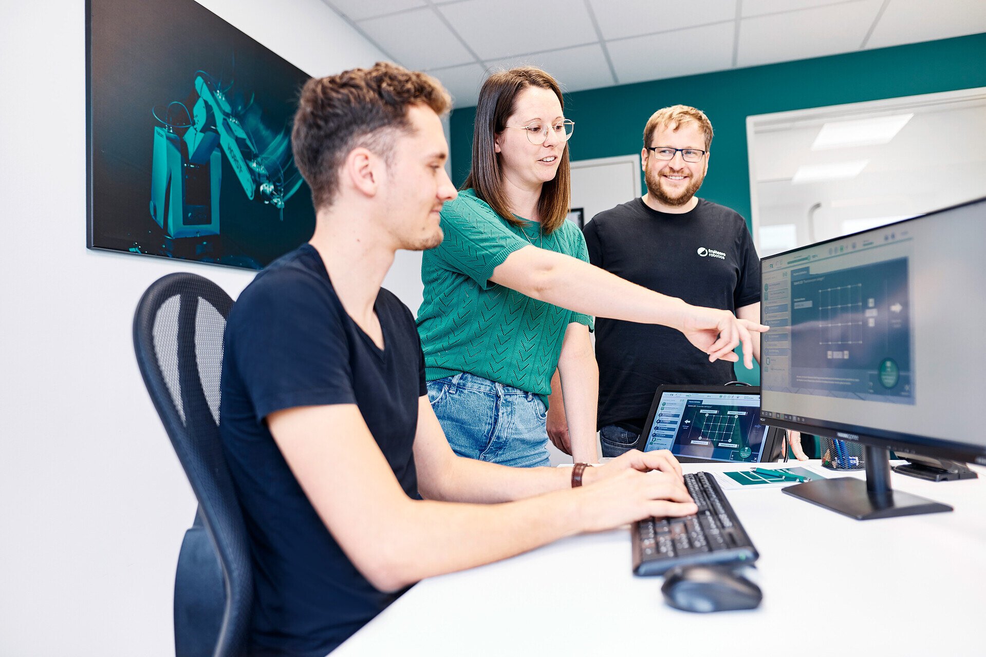 Three people looking at a screen in an office