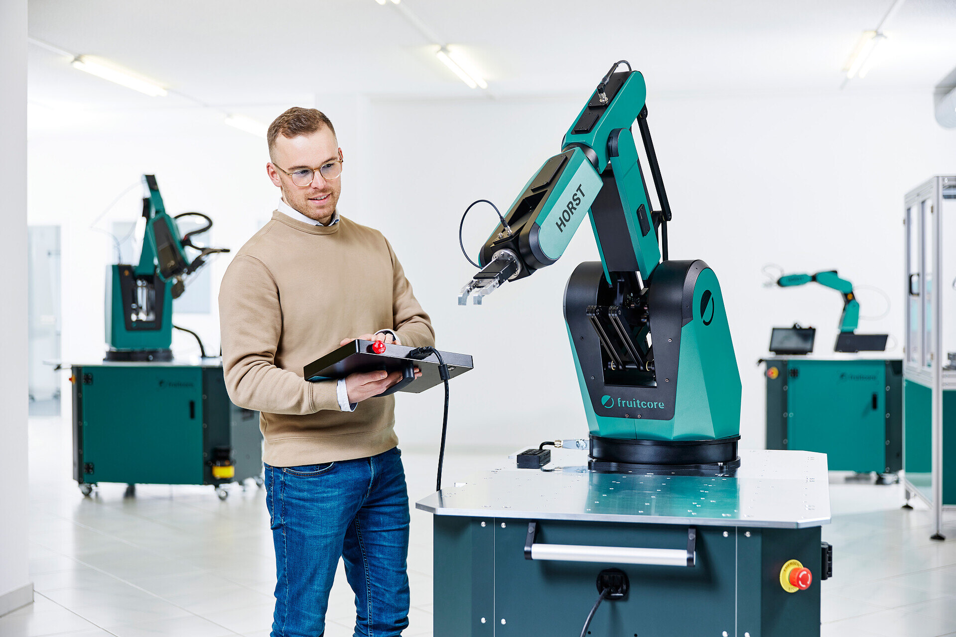 A man holding a control panel standing next to a HORST Robot 