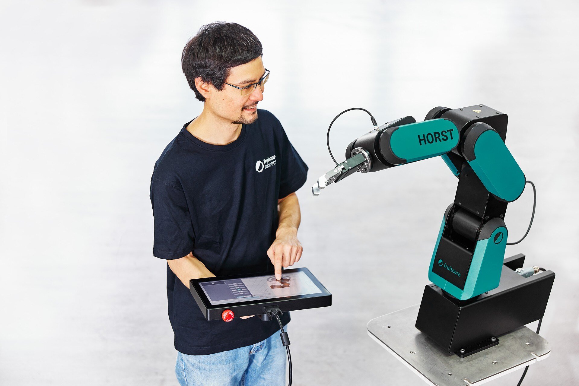 A man holding a control panel in his hand and adjusts the robot.